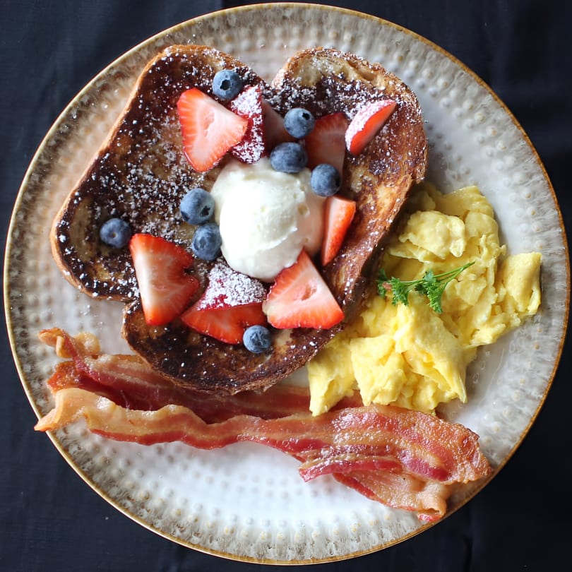 Sage Social Eatery's French toast with berries, whipped cream, scrambled eggs, and bacon.