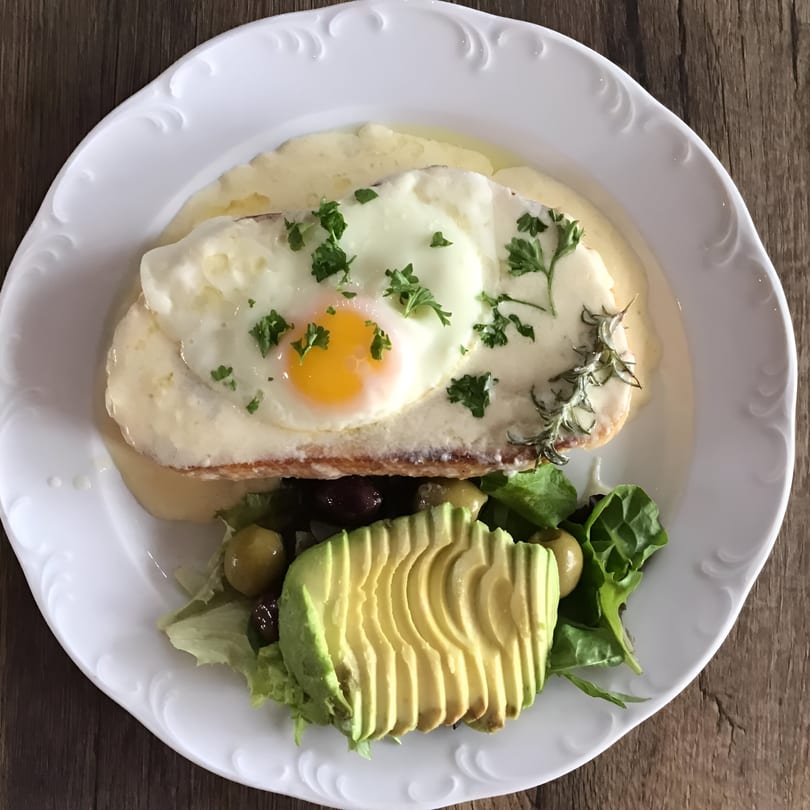 Sage Social Eatery's brunch dish with a fried egg, avocado, and salad on a white plate.