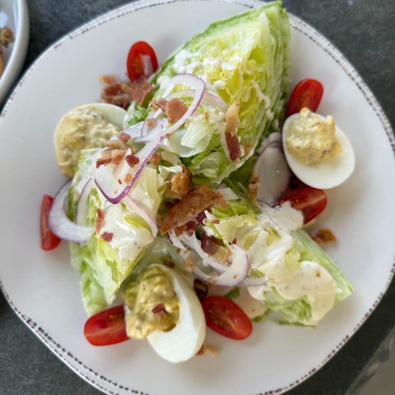 Sage Social Eatery's wedge salad with lettuce, bacon, red onion, cherry tomatoes, and deviled eggs.
